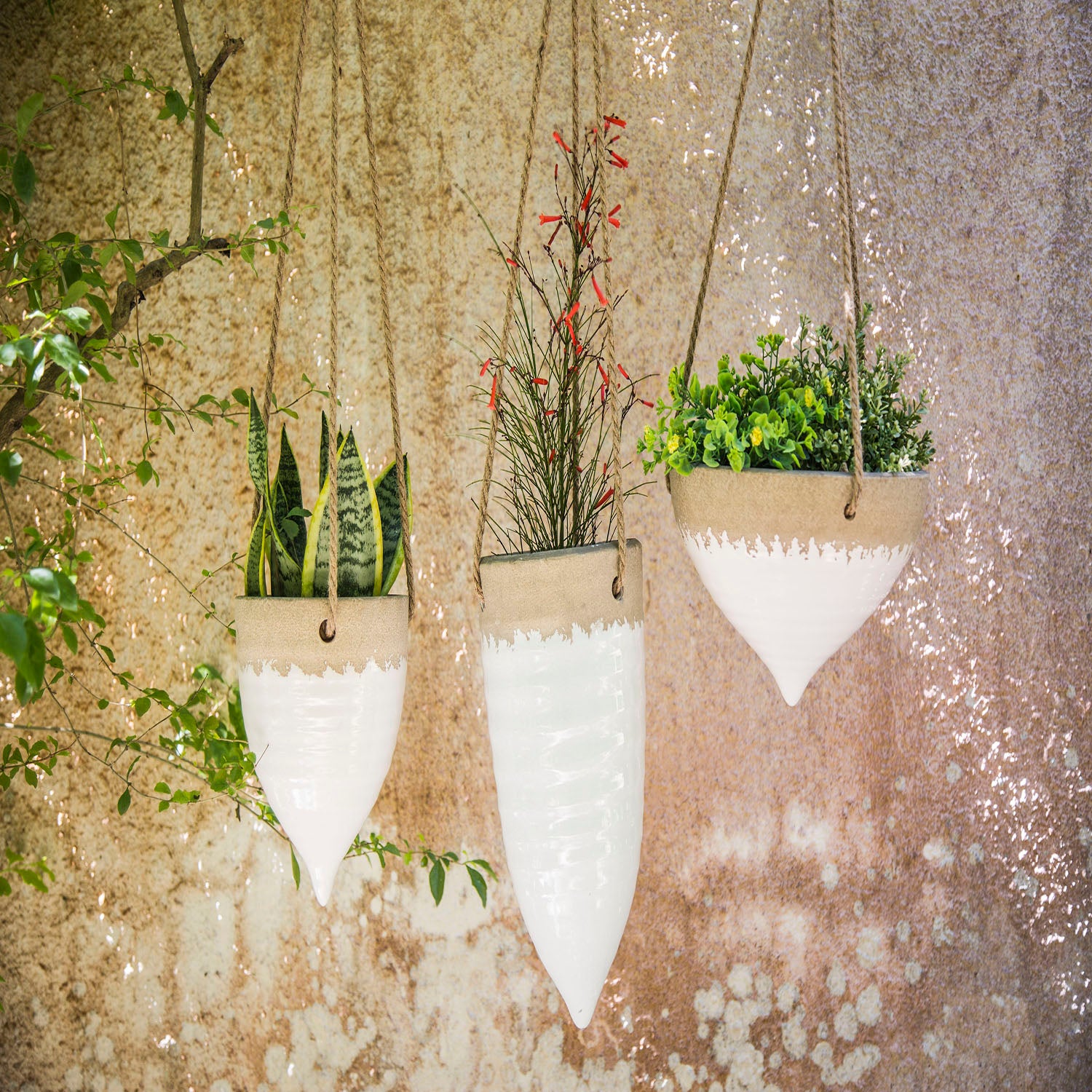 A white stoneware hanging planter with jute rope